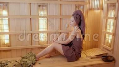 年轻女子穿着毛巾在桑拿浴室里放松。 新芬兰桑拿浴室内部，医疗用红外<strong>线面</strong>板